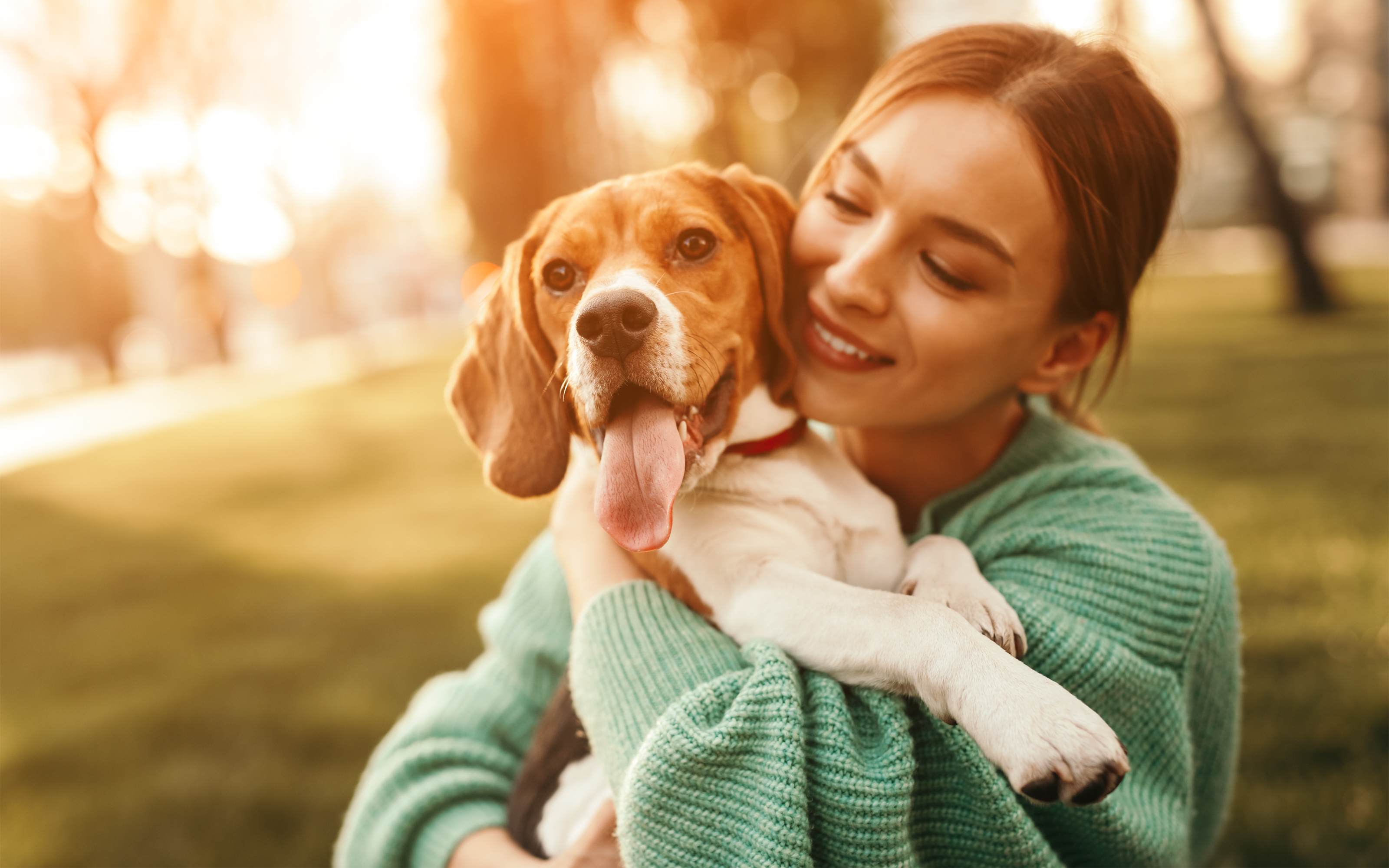 Happy woman embracing beagle dog in park